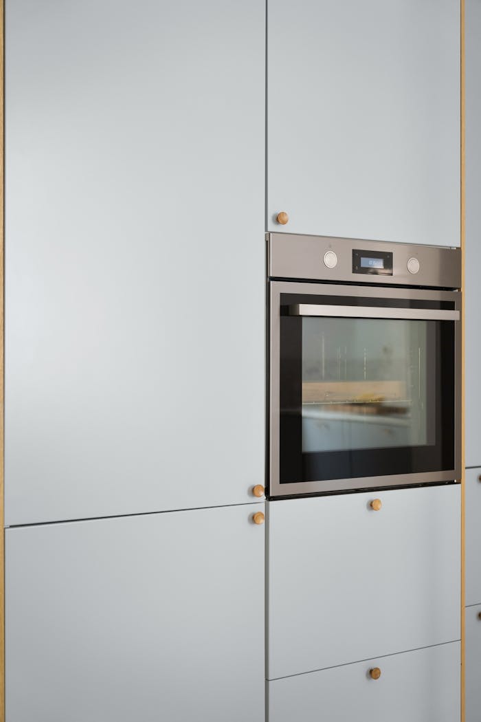 A sleek and modern kitchen cabinet with a stainless steel built-in oven, showcasing minimalist interior design.