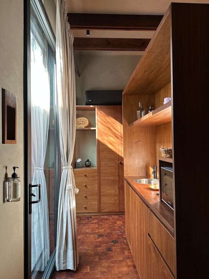 Bright and elegant small kitchen with wood cabinetry and natural light streaming through glass doors.